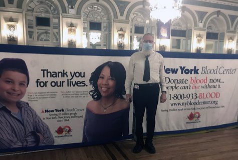 Man standing in front of NYBC sign that reads, "Thank you for our lives"
